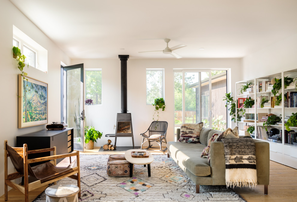 Bild på ett minimalistiskt vardagsrum, med ljust trägolv, en öppen vedspis och en väggmonterad TV