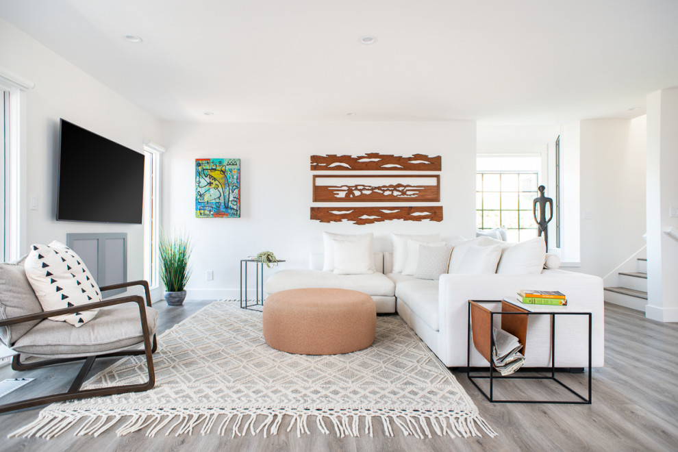 На фото: большая открытая гостиная комната в стиле модернизм с домашним баром, белыми стенами, полом из винила, телевизором на стене и серым полом без камина