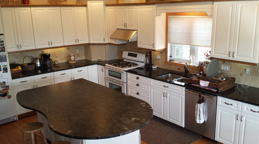 Inspiration for a large transitional l-shaped dark wood floor and brown floor eat-in kitchen remodel with an undermount sink, raised-panel cabinets, white cabinets, quartz countertops, beige backsplash, stone tile backsplash, white appliances and an island