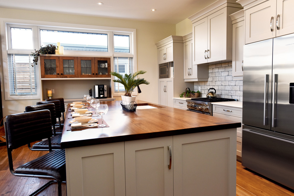 Inspiration for a mid-sized craftsman medium tone wood floor kitchen remodel in Toronto with a double-bowl sink, recessed-panel cabinets, gray cabinets, solid surface countertops, multicolored backsplash, porcelain backsplash, stainless steel appliances, an island and white countertops