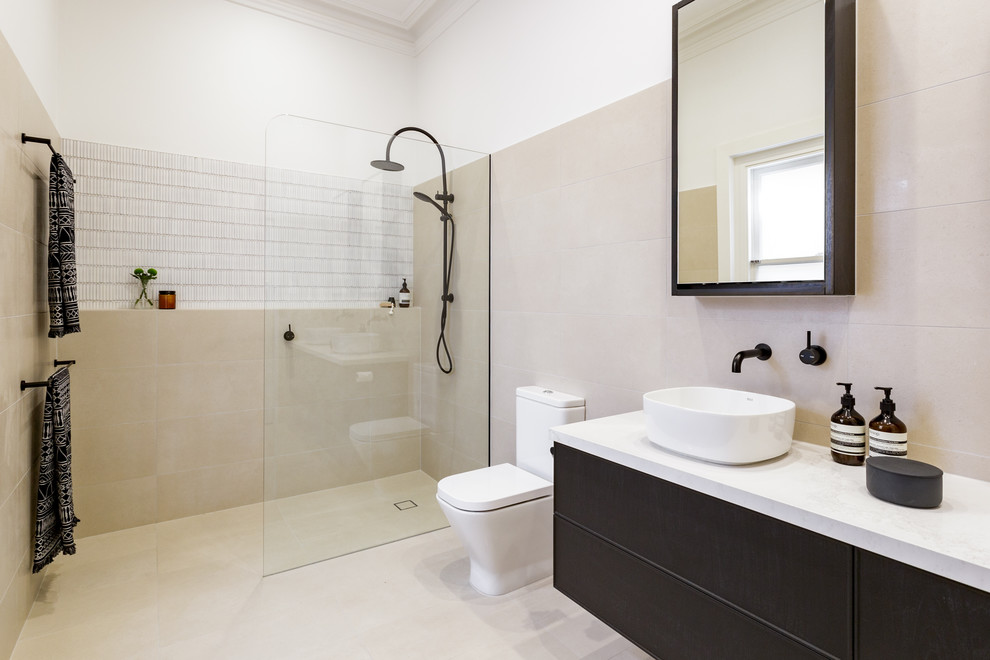 Photo of a mid-sized modern 3/4 bathroom in Melbourne with beaded inset cabinets, black cabinets, an open shower, cement tile, a vessel sink, stainless steel benchtops and white benchtops.