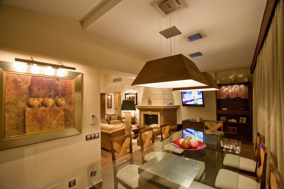 Imagen de comedor de cocina mediterráneo de tamaño medio con paredes beige, suelo de madera oscura, todas las chimeneas y marco de chimenea de ladrillo