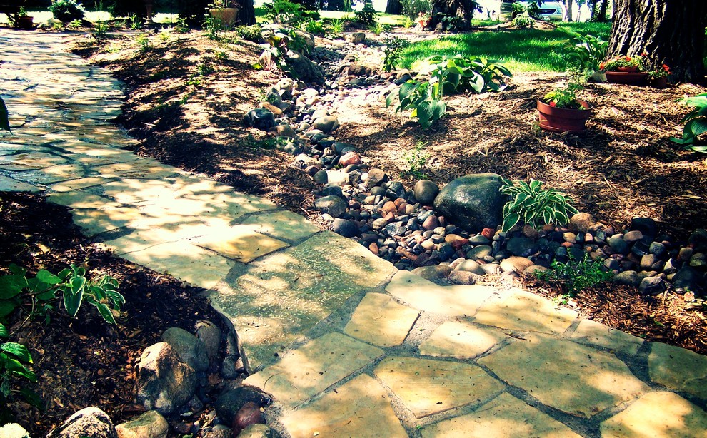 This is an example of a large country backyard partial sun garden for summer in Minneapolis with a garden path and natural stone pavers.