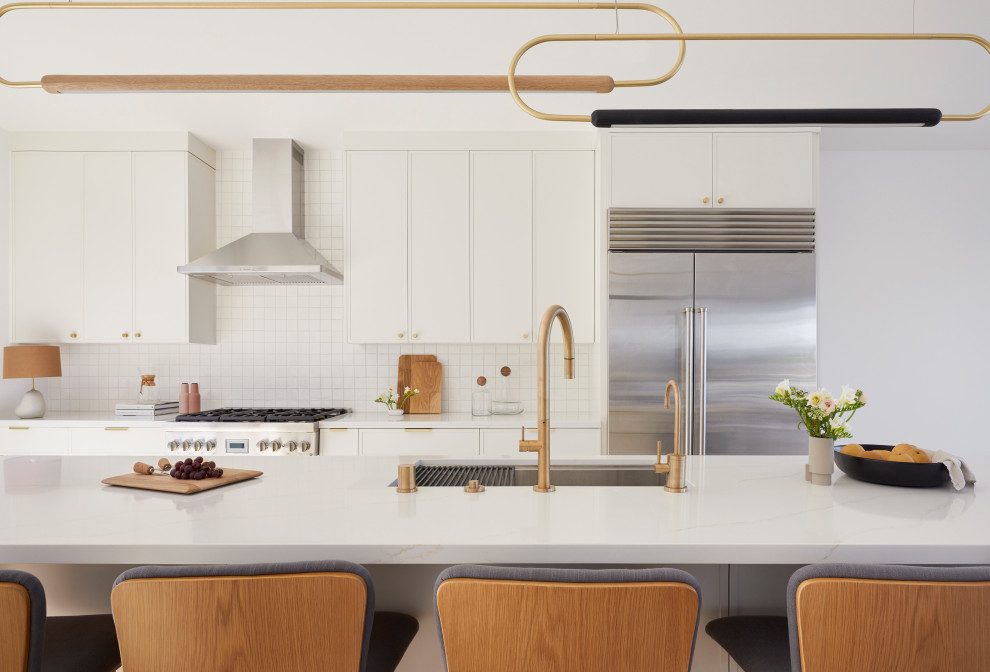 Medium sized contemporary kitchen/diner in San Francisco with a submerged sink, shaker cabinets, white cabinets, engineered stone countertops, white splashback, ceramic splashback, stainless steel appliances, an island, white worktops, light hardwood flooring and brown floors.