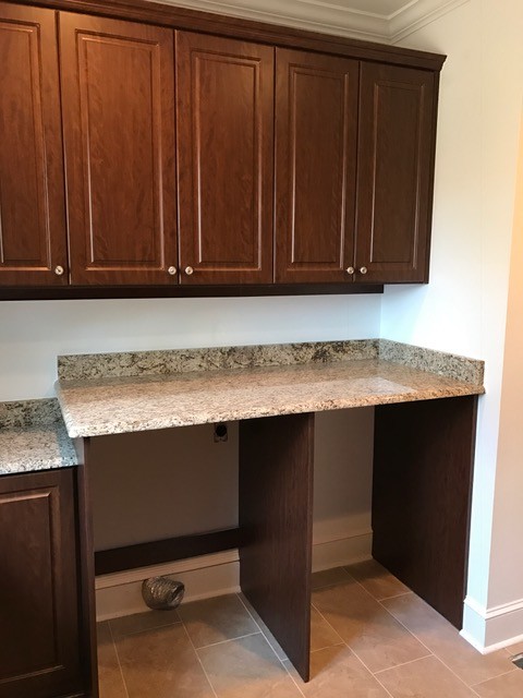 Design ideas for a large traditional u-shaped utility room in Atlanta with raised-panel cabinets, dark wood cabinets, granite benchtops, beige walls, ceramic floors, a side-by-side washer and dryer, an undermount sink, beige floor and brown benchtop.