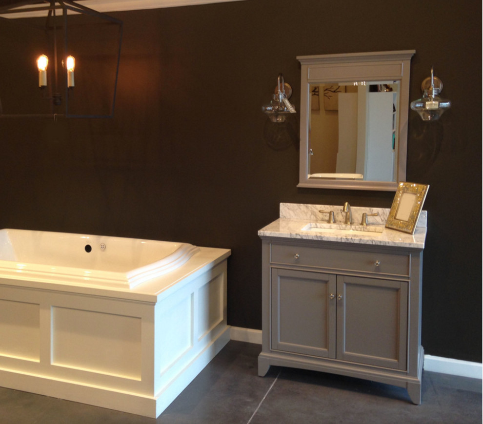 Inspiration for a large transitional master concrete floor drop-in bathtub remodel with recessed-panel cabinets, brown walls, an undermount sink, marble countertops and gray cabinets