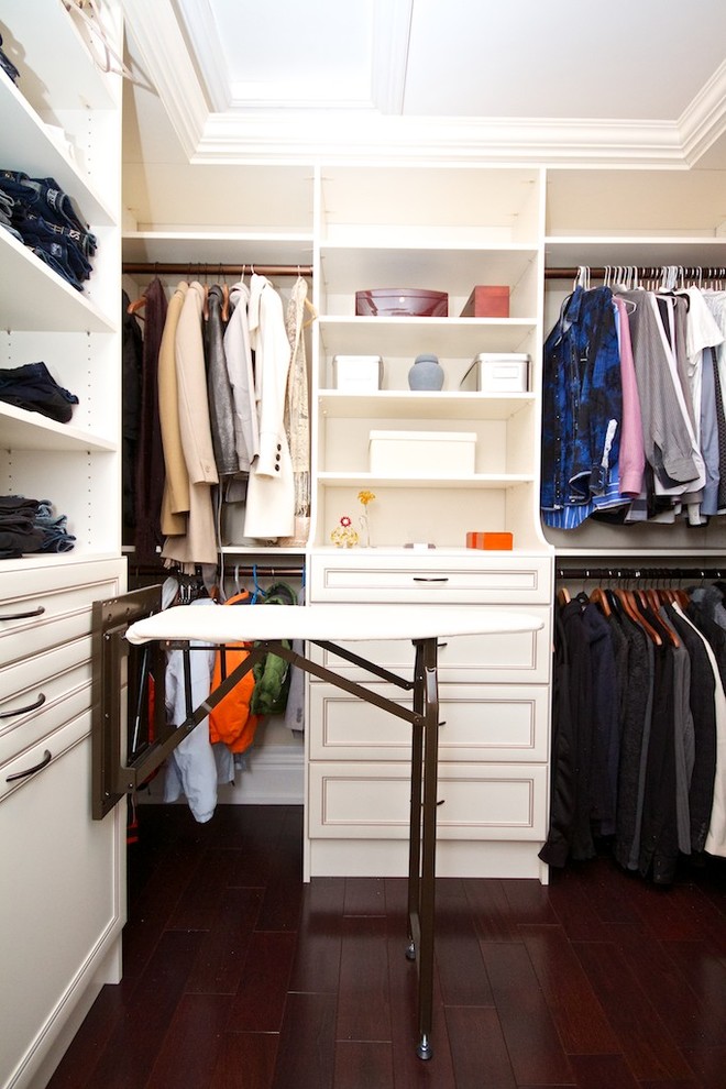 This is an example of a traditional walk-in wardrobe in Toronto with beige cabinets and dark hardwood floors.