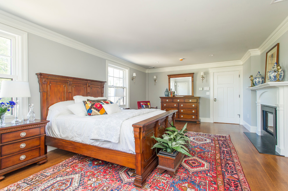Traditional bedroom in Boston with grey walls, dark hardwood floors and a standard fireplace.
