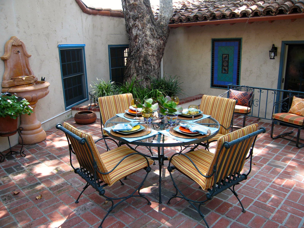 Mediterranean patio in Orange County with brick pavers and a water feature.