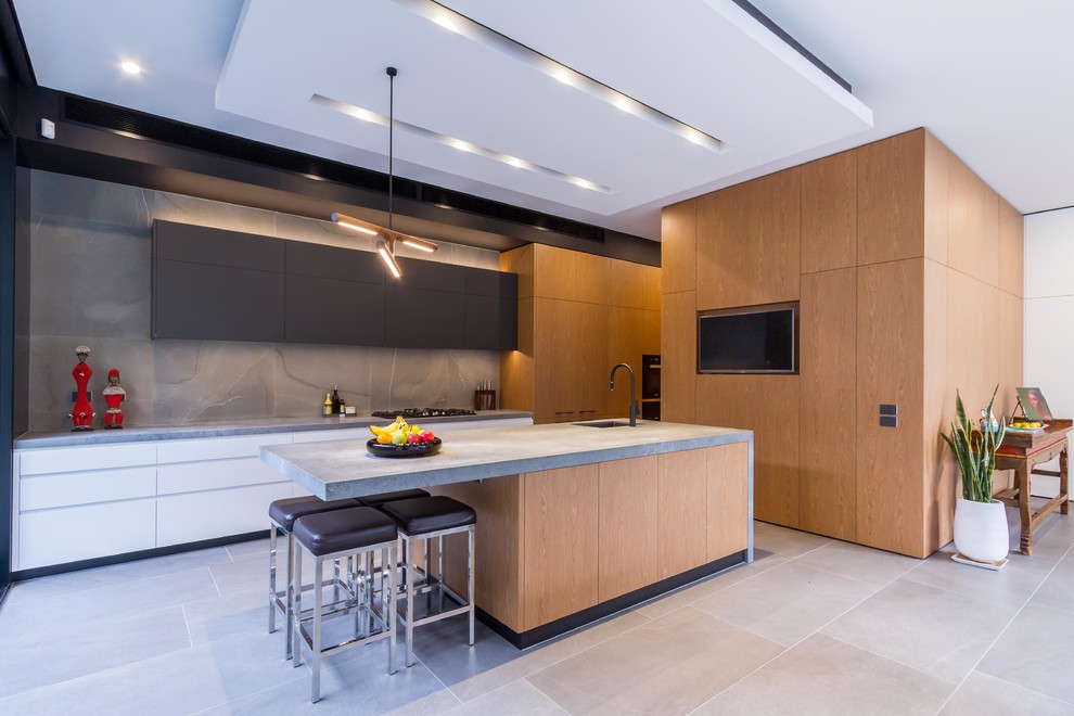 Photo of a large contemporary galley open plan kitchen in Melbourne with an undermount sink, flat-panel cabinets, medium wood cabinets, quartz benchtops, grey splashback, porcelain splashback, black appliances, porcelain floors, with island, grey floor and grey benchtop.