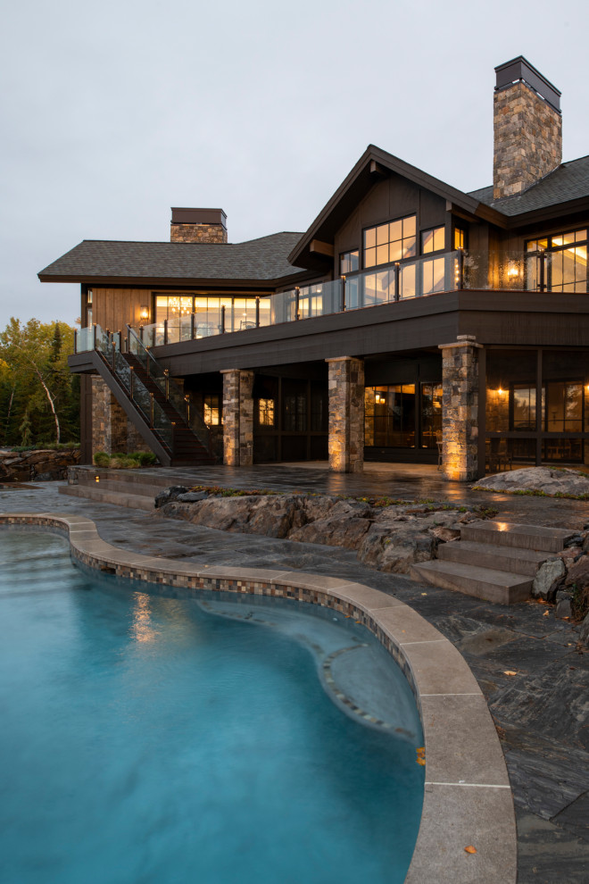 Photo of a country custom-shaped infinity pool in Minneapolis with natural stone pavers.
