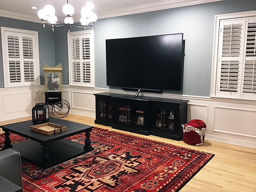 Large transitional enclosed family room in Orlando with blue walls, light hardwood floors, a wall-mounted tv, beige floor and decorative wall panelling.