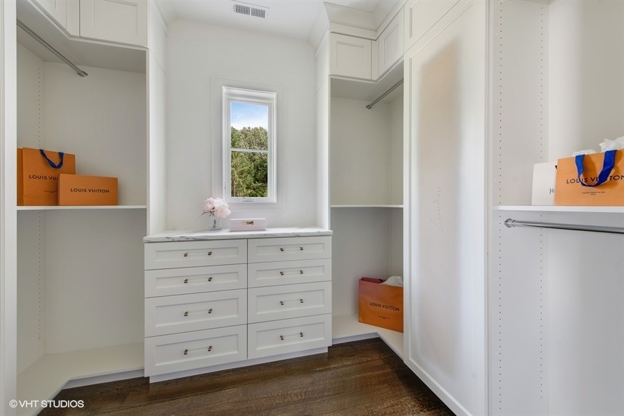 Example of a large transitional women's medium tone wood floor and brown floor walk-in closet design in Chicago with recessed-panel cabinets and white cabinets