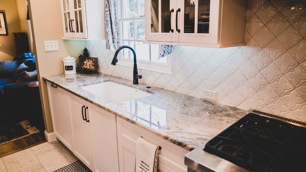 Eat-in kitchen - mid-sized transitional porcelain tile and beige floor eat-in kitchen idea with an undermount sink, shaker cabinets, white cabinets, quartzite countertops, white backsplash, ceramic backsplash, stainless steel appliances, an island and multicolored countertops