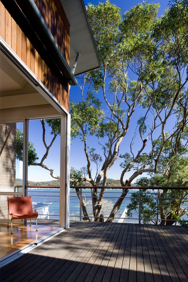 This is an example of a mid-sized contemporary courtyard patio in Sydney with decking and an awning.