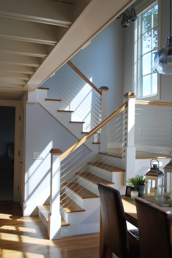 This is an example of a mid-sized beach style wood l-shaped staircase in Providence with wood risers and cable railing.