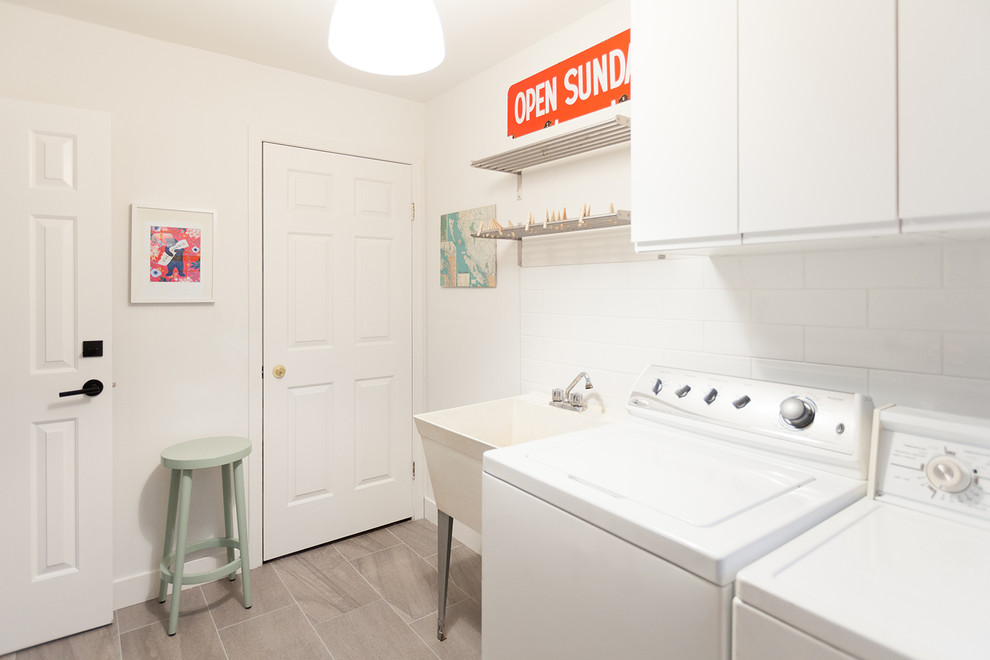 Design ideas for a mid-sized transitional galley utility room in Vancouver with an utility sink, flat-panel cabinets, white cabinets, white walls, a side-by-side washer and dryer, grey floor, white splashback and subway tile splashback.