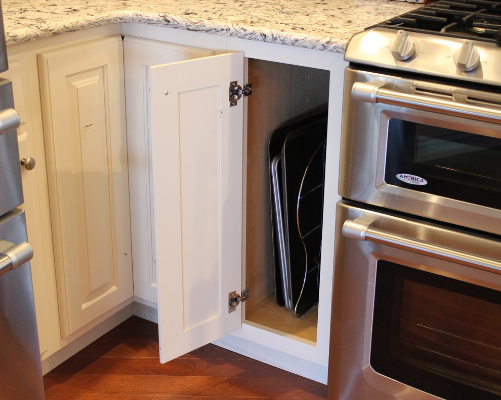 Large mountain style l-shaped light wood floor open concept kitchen photo in Chicago with a farmhouse sink, raised-panel cabinets, white cabinets, quartz countertops, stainless steel appliances and an island