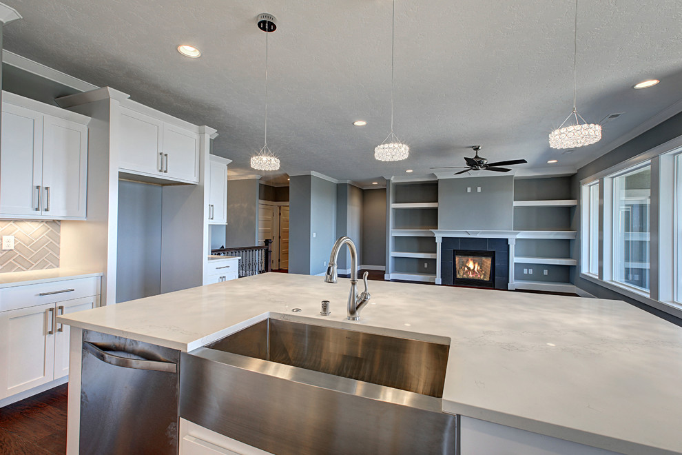 Inspiration for a mid-sized transitional l-shaped medium tone wood floor open concept kitchen remodel in Seattle with a farmhouse sink, shaker cabinets, white cabinets, quartz countertops, gray backsplash, glass tile backsplash, stainless steel appliances and an island