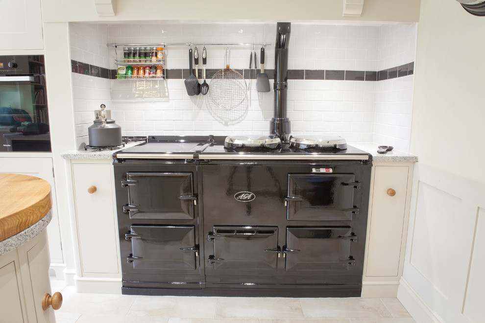 This is an example of a mid-sized traditional l-shaped eat-in kitchen in Essex with a farmhouse sink, recessed-panel cabinets, white cabinets, granite benchtops, glass sheet splashback, ceramic floors and with island.