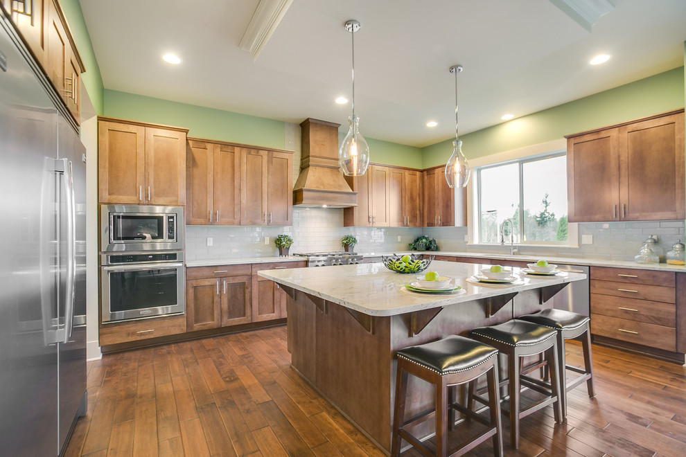 Example of a transitional u-shaped dark wood floor eat-in kitchen design in Seattle with flat-panel cabinets, an island, dark wood cabinets, granite countertops, gray backsplash, glass tile backsplash, stainless steel appliances and an undermount sink