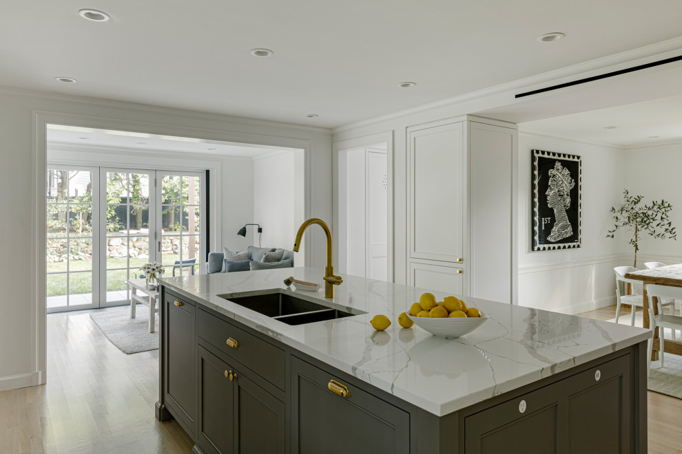 Inspiration for a mid-sized transitional l-shaped light wood floor open concept kitchen remodel in Boston with a single-bowl sink, recessed-panel cabinets, gray cabinets, quartz countertops, white backsplash, quartz backsplash, an island and white countertops