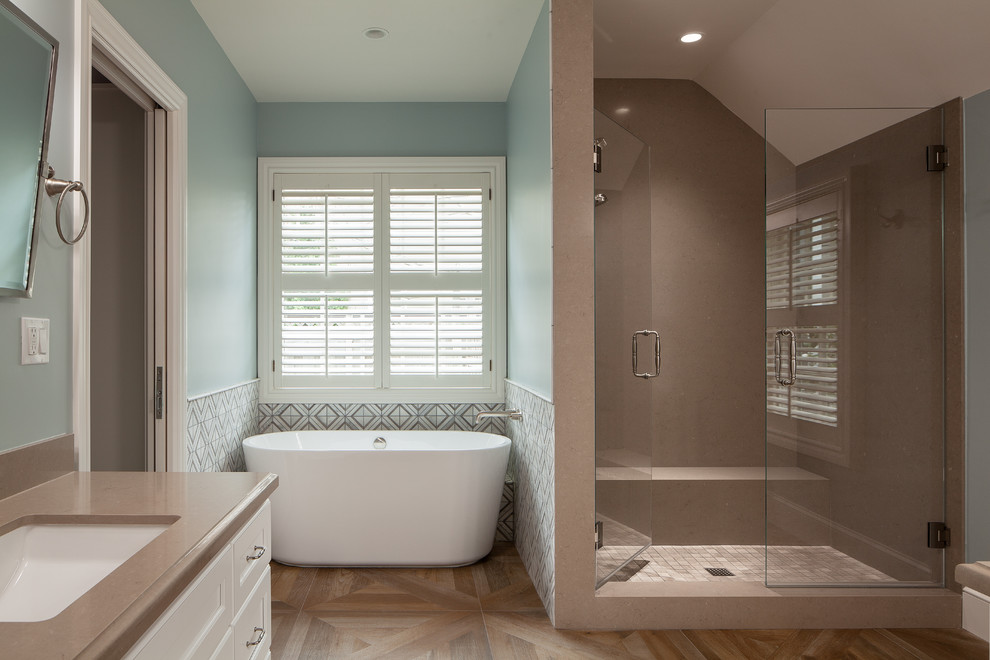 Design ideas for a mid-sized transitional master wet room bathroom in San Francisco with recessed-panel cabinets, white cabinets, a freestanding tub, a one-piece toilet, beige tile, stone slab, green walls, porcelain floors, a drop-in sink, quartzite benchtops, brown floor, a hinged shower door and beige benchtops.