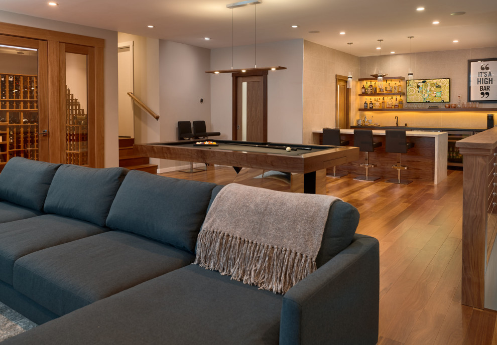 Example of a large minimalist medium tone wood floor and brown floor basement game room design in San Francisco with a bar, a home theater and beige walls