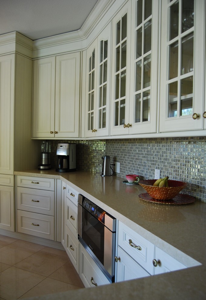 Mid-sized transitional l-shaped limestone floor eat-in kitchen photo with an undermount sink, recessed-panel cabinets, white cabinets, quartz countertops, multicolored backsplash, glass sheet backsplash, paneled appliances and an island
