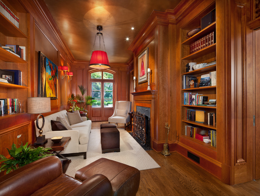 Design ideas for a mid-sized traditional enclosed family room in DC Metro with dark hardwood floors, a library, brown walls, a standard fireplace, a wood fireplace surround and no tv.