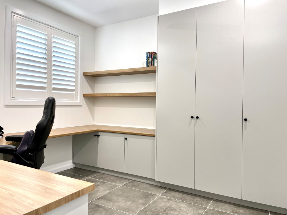 Immagine di un grande ufficio moderno con pareti bianche, pavimento con piastrelle in ceramica, scrivania incassata e pavimento grigio