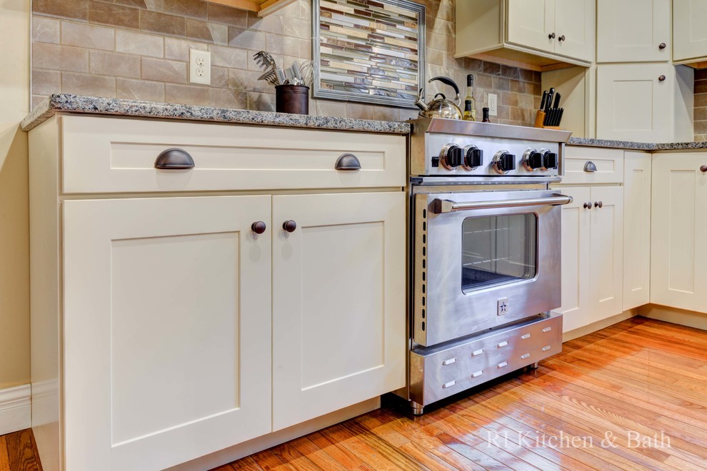 Example of a large transitional u-shaped light wood floor eat-in kitchen design in Providence with an undermount sink, shaker cabinets, beige cabinets, granite countertops, brown backsplash, porcelain backsplash, stainless steel appliances and an island