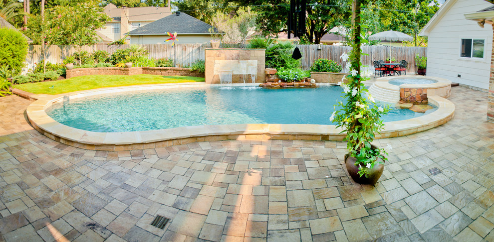 Design ideas for a large traditional backyard kidney-shaped pool in Houston with a hot tub and natural stone pavers.