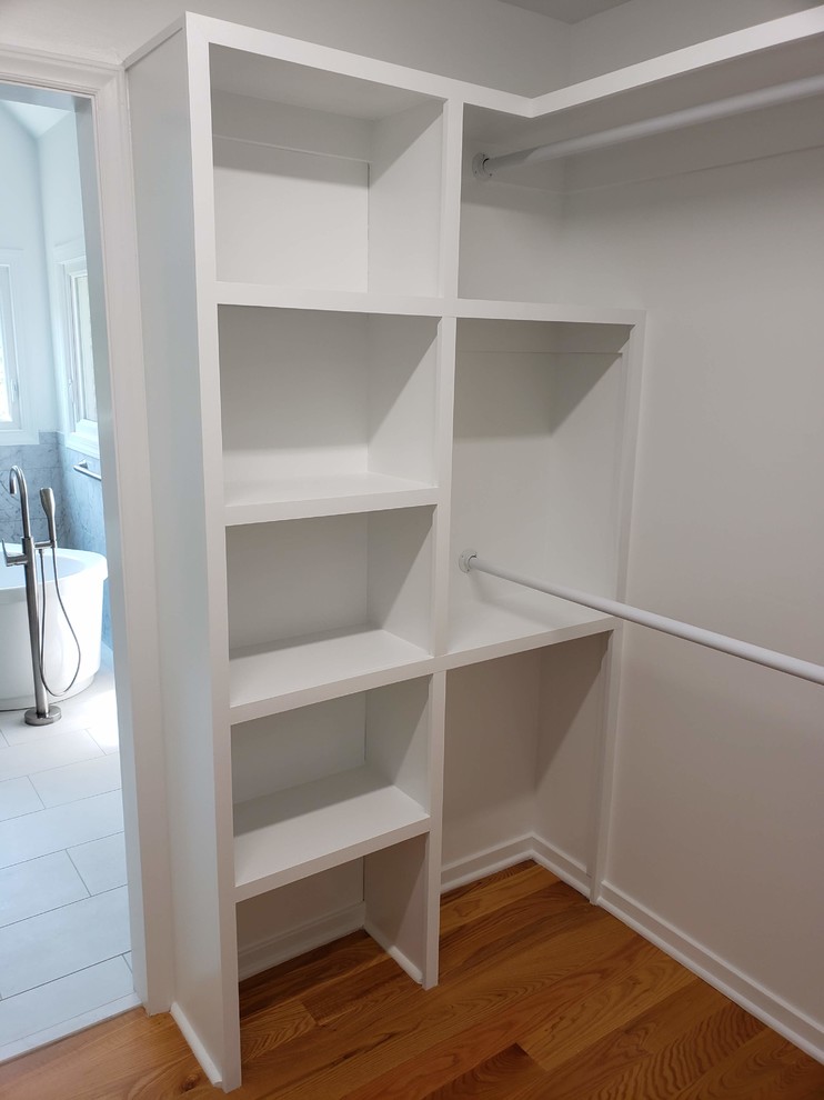 Mid-sized contemporary gender-neutral walk-in wardrobe in Raleigh with open cabinets, white cabinets, medium hardwood floors and brown floor.