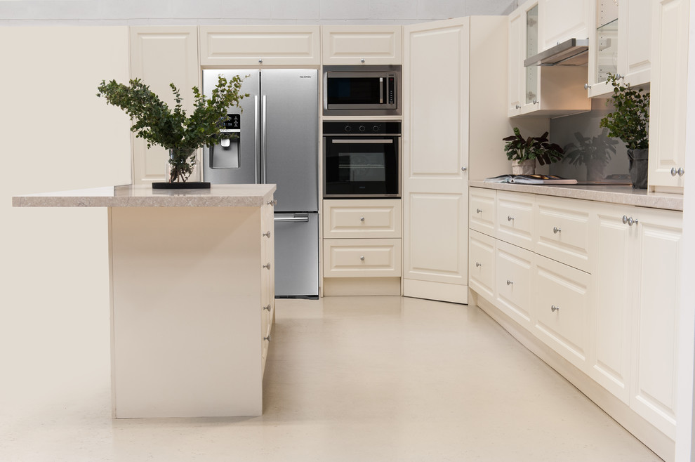 Photo of a mid-sized traditional u-shaped kitchen pantry in Melbourne with raised-panel cabinets, quartz benchtops, grey splashback, glass sheet splashback, stainless steel appliances, concrete floors, with island, beige floor and beige benchtop.