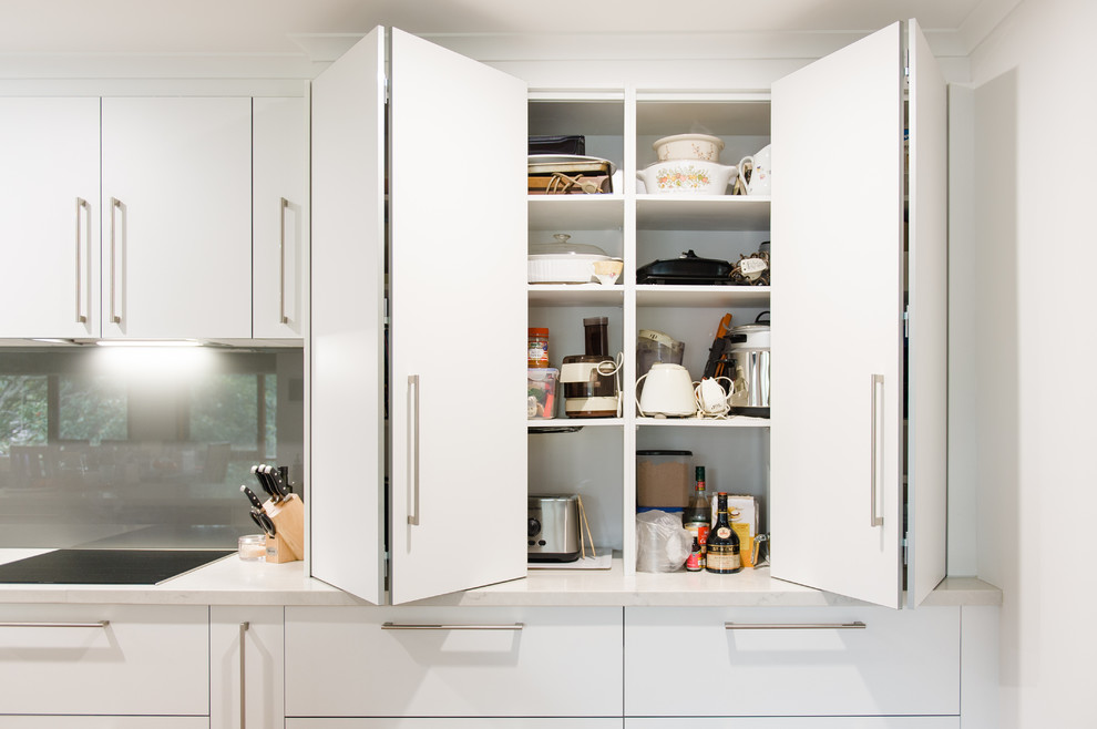 This is an example of a large modern u-shaped kitchen pantry in Melbourne with a double-bowl sink, open cabinets, white cabinets, quartz benchtops, metallic splashback, glass sheet splashback, stainless steel appliances, medium hardwood floors, with island and beige benchtop.