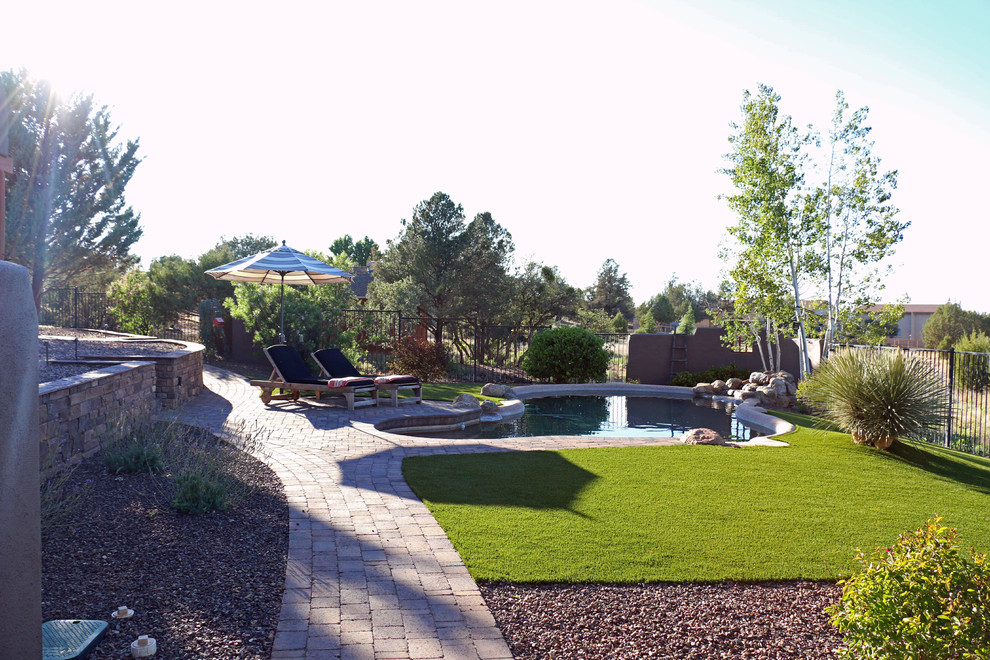 Inspiration for a large backyard custom-shaped pool in Phoenix with a water feature and brick pavers.