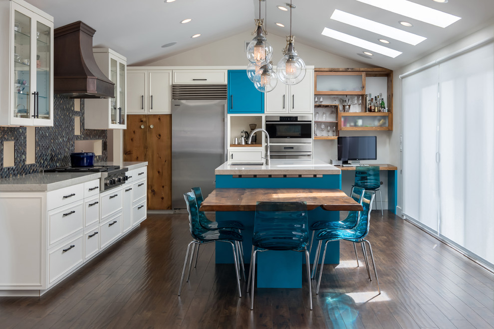 This is an example of a transitional l-shaped eat-in kitchen in San Francisco with an undermount sink, recessed-panel cabinets, blue cabinets, blue splashback, mosaic tile splashback, stainless steel appliances, dark hardwood floors, with island, brown floor and grey benchtop.