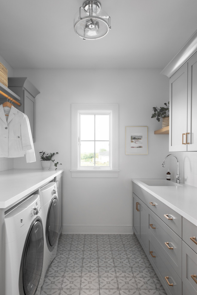 Klassisk inredning av en mellanstor vita parallell vitt tvättstuga, med en undermonterad diskho, skåp i shakerstil, grå skåp, bänkskiva i kvarts, vita väggar, klinkergolv i keramik, flerfärgat golv och en tvättmaskin och torktumlare bredvid varandra