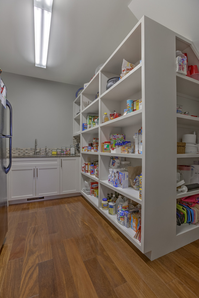 Medium tone wood floor eat-in kitchen photo with white cabinets, granite countertops, multicolored backsplash and an island
