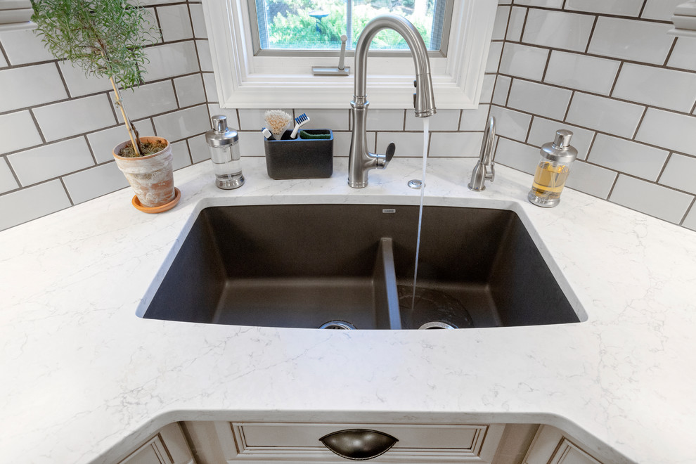 Example of a mid-sized transitional l-shaped medium tone wood floor and red floor eat-in kitchen design with an undermount sink, raised-panel cabinets, gray cabinets, quartz countertops, gray backsplash, subway tile backsplash, stainless steel appliances, an island and white countertops
