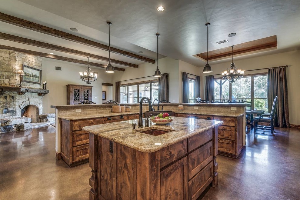 Inspiration for a mid-sized country l-shaped open plan kitchen in Austin with a farmhouse sink, shaker cabinets, dark wood cabinets, granite benchtops, grey splashback, ceramic splashback, stainless steel appliances, concrete floors, multiple islands, brown floor and brown benchtop.
