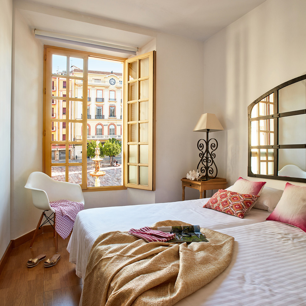 Mid-sized mediterranean guest bedroom in Malaga with white walls, medium hardwood floors and no fireplace.