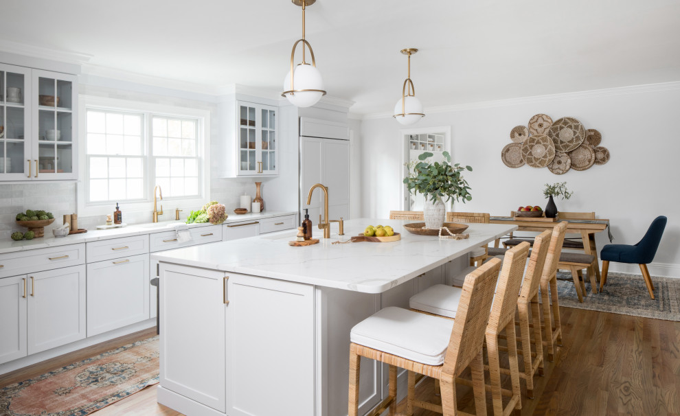 Design ideas for a large transitional eat-in kitchen in New York with shaker cabinets, white cabinets, quartz benchtops, white splashback, ceramic splashback, stainless steel appliances, medium hardwood floors, with island, brown floor and white benchtop.
