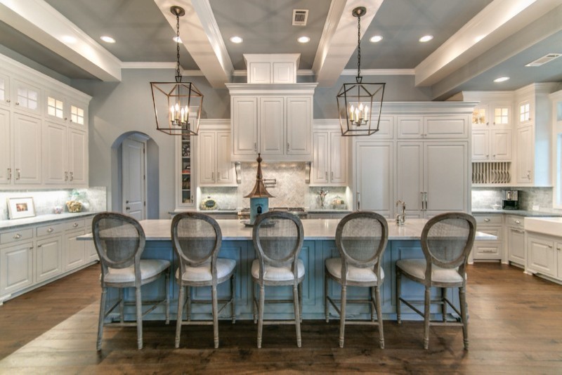 Expansive arts and crafts u-shaped eat-in kitchen in Houston with a farmhouse sink, raised-panel cabinets, white cabinets, marble benchtops, grey splashback, marble splashback, panelled appliances, dark hardwood floors, with island and brown floor.