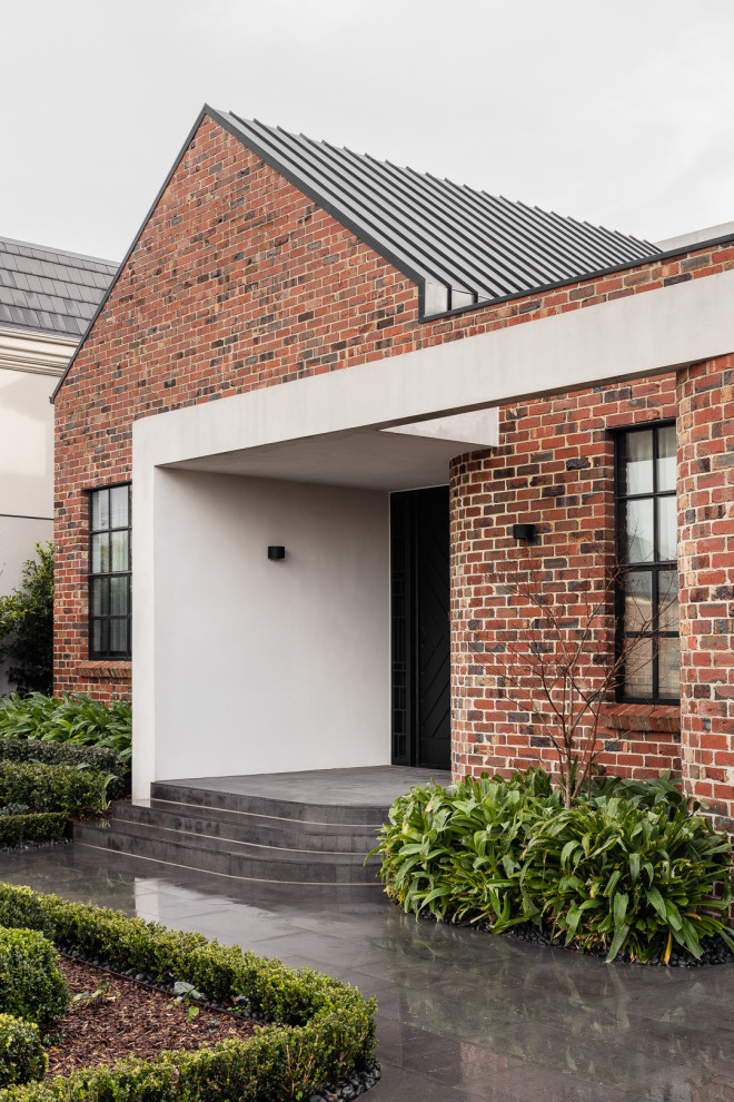 This is an example of a large contemporary two-storey brick house exterior in Melbourne with a metal roof.