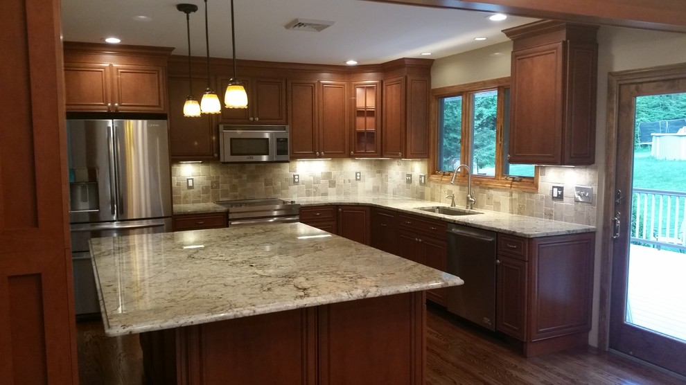 Inspiration for a mid-sized traditional u-shaped kitchen in New York with an undermount sink, beaded inset cabinets, medium wood cabinets, granite benchtops, stone tile splashback, stainless steel appliances, with island, beige splashback, dark hardwood floors and brown floor.