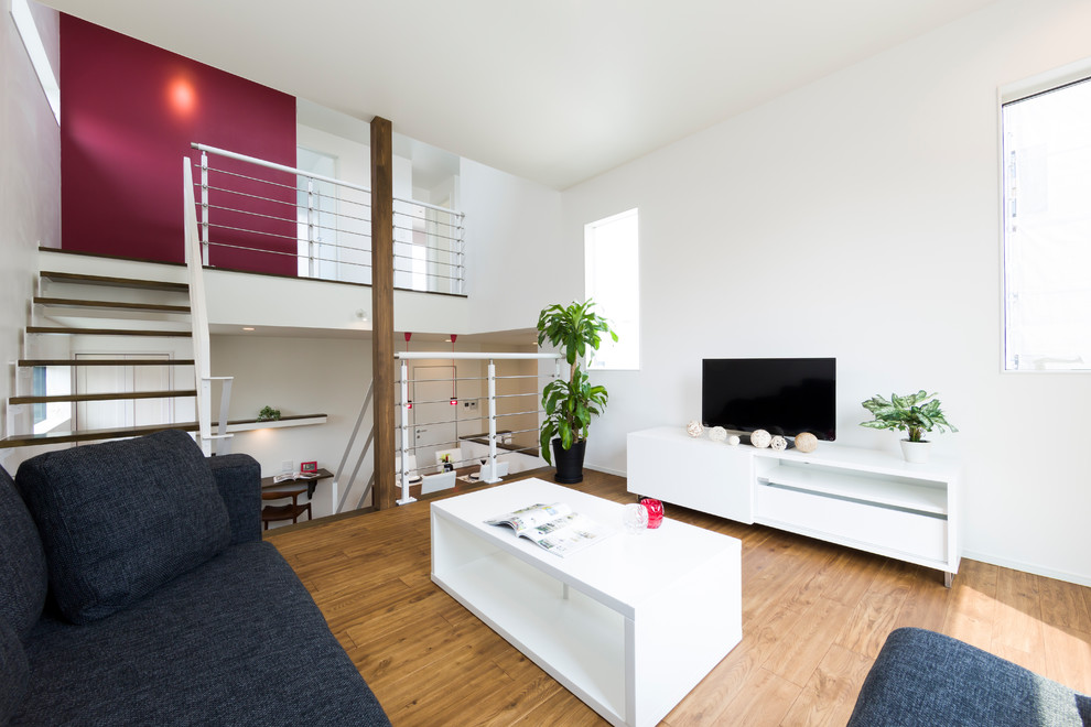 This is an example of a modern open concept living room in Other with white walls, medium hardwood floors, a freestanding tv and brown floor.
