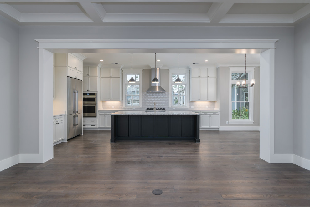 Inspiration for a transitional brown floor eat-in kitchen remodel with white cabinets, gray backsplash, subway tile backsplash, stainless steel appliances, an island and white countertops