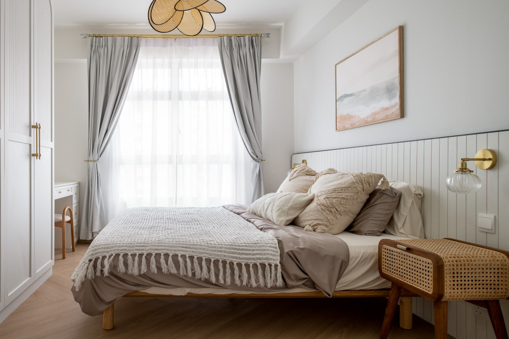 Skandinavisk inredning av ett sovrum, med vita väggar, mellanmörkt trägolv och brunt golv